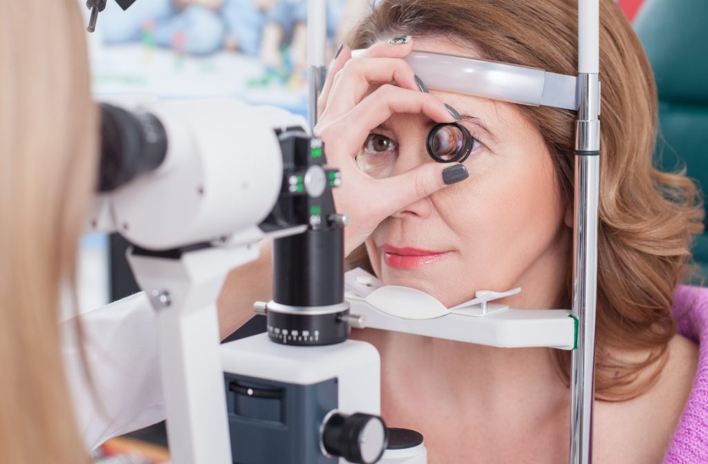 A woman undergoing an annual eye exam while her optometrist is using a tool to magnify her eye to examine more closely