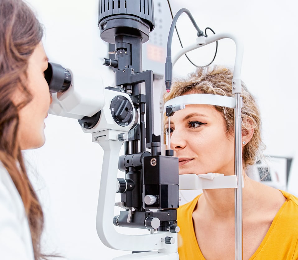 A female optometrist examines a female patient's eyes during an eye exam.