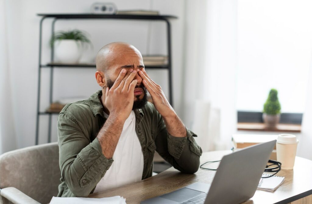 A man rubbing his eyes while working in his office.